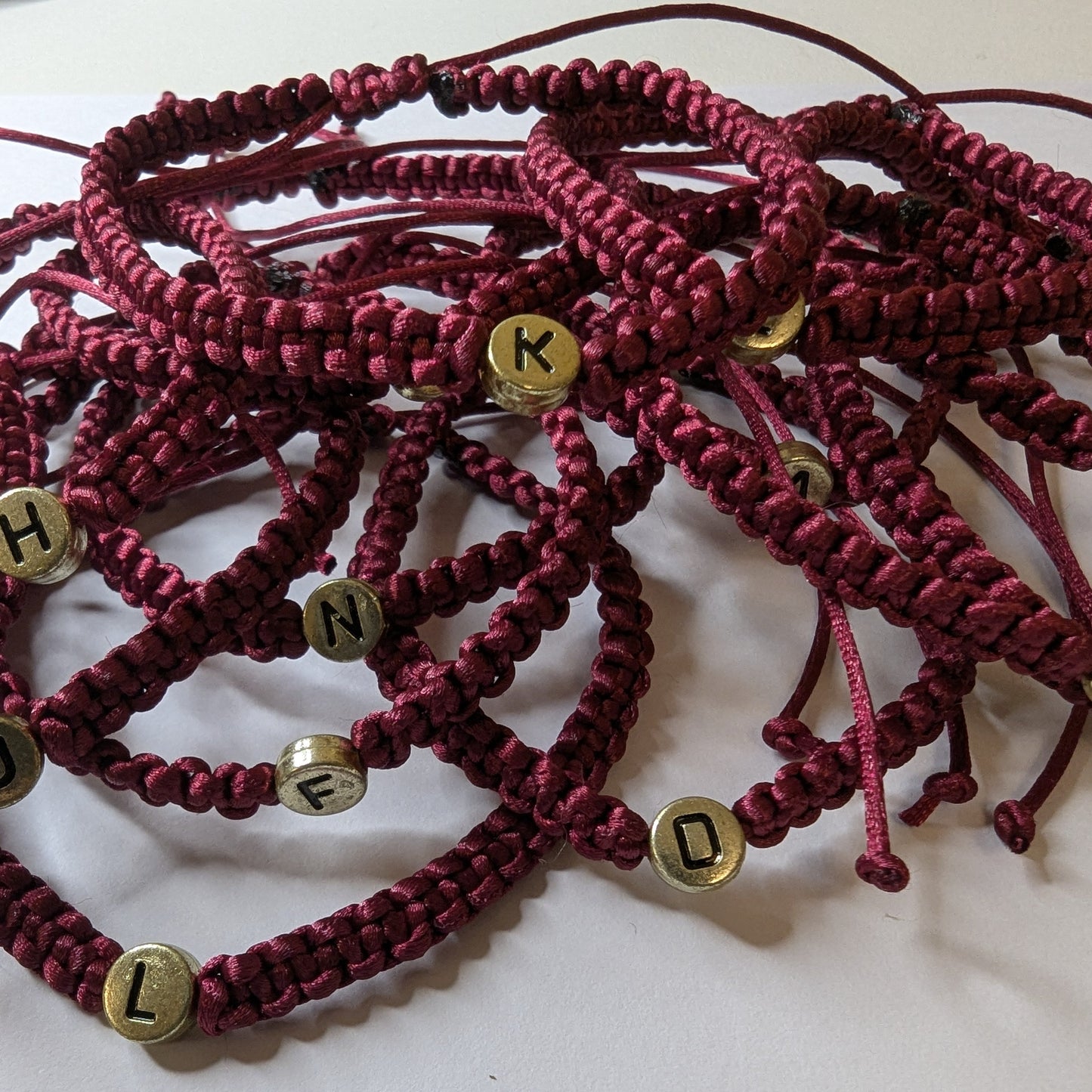 Maroon braided bracelets with gold letter beads 