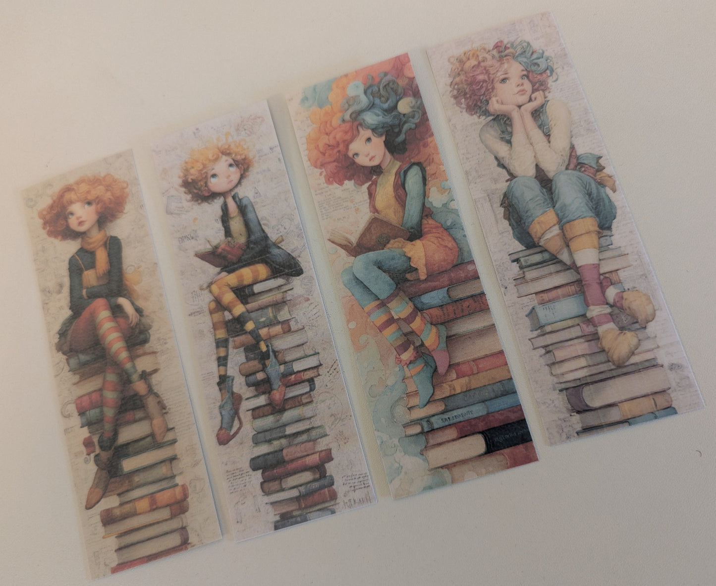 Four colorful bookmarks with illustrations of a girl sitting on books on a white background