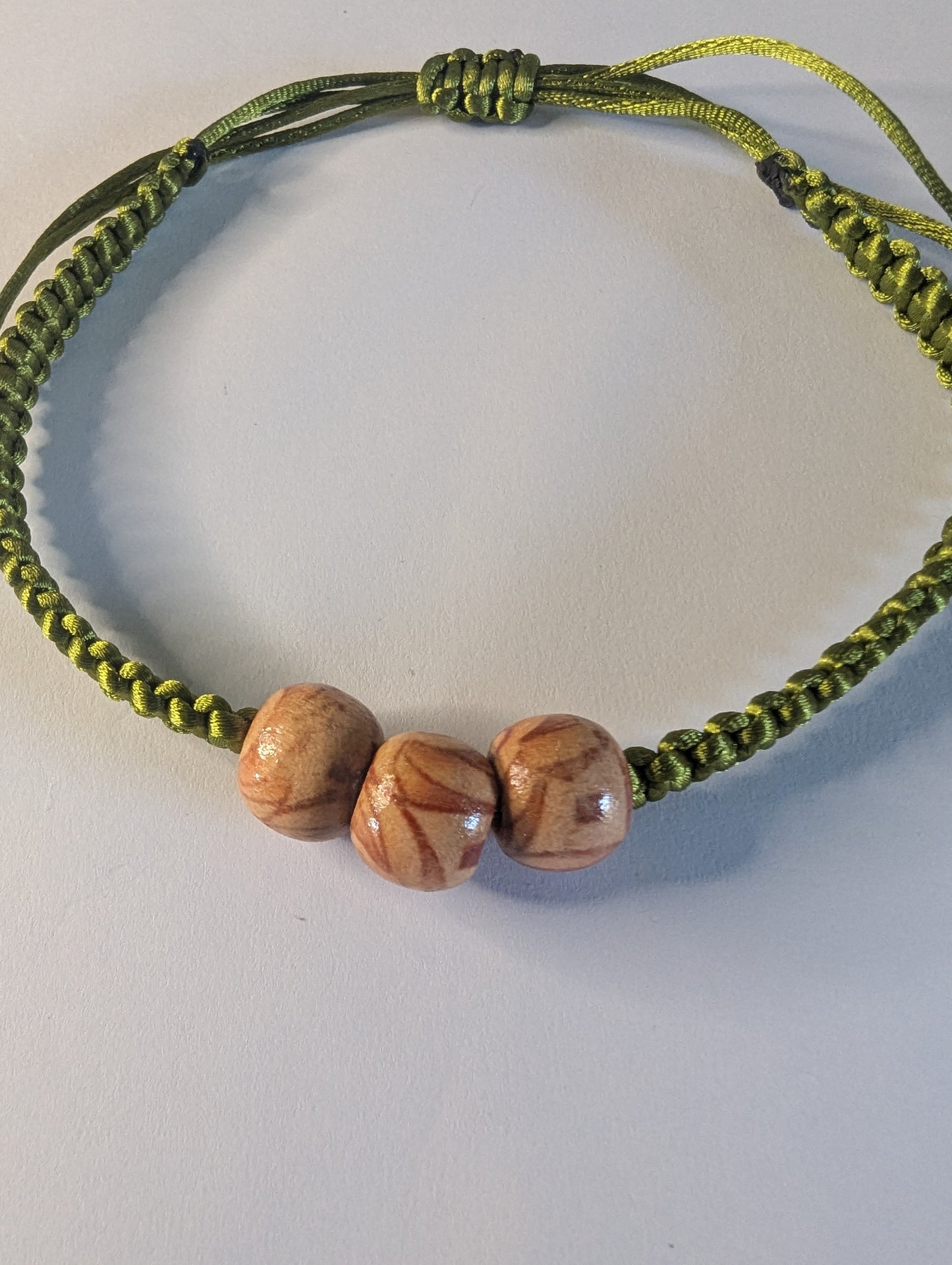 Bracelet with wooden beads on a green cord.