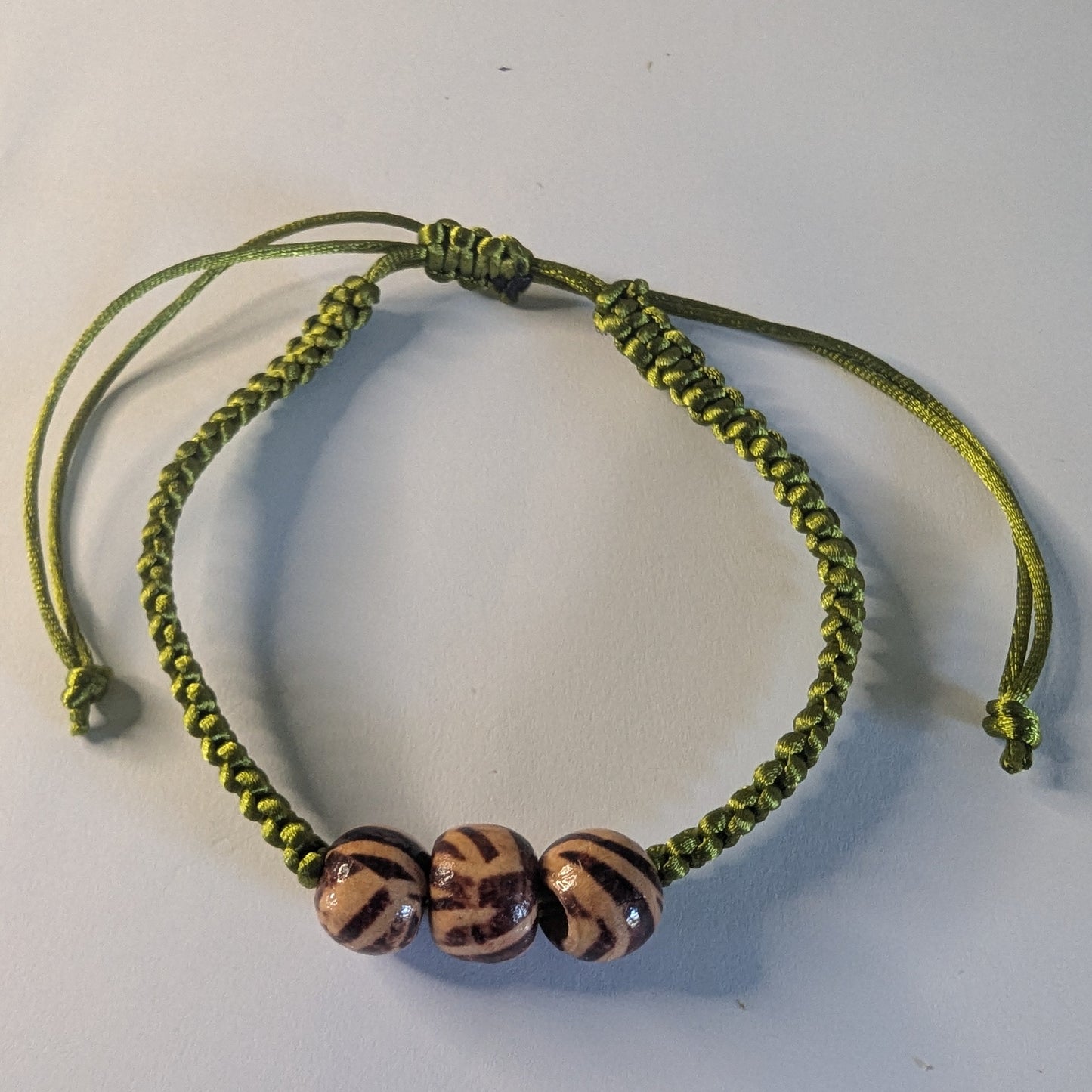 Green braided bracelet with three beads.