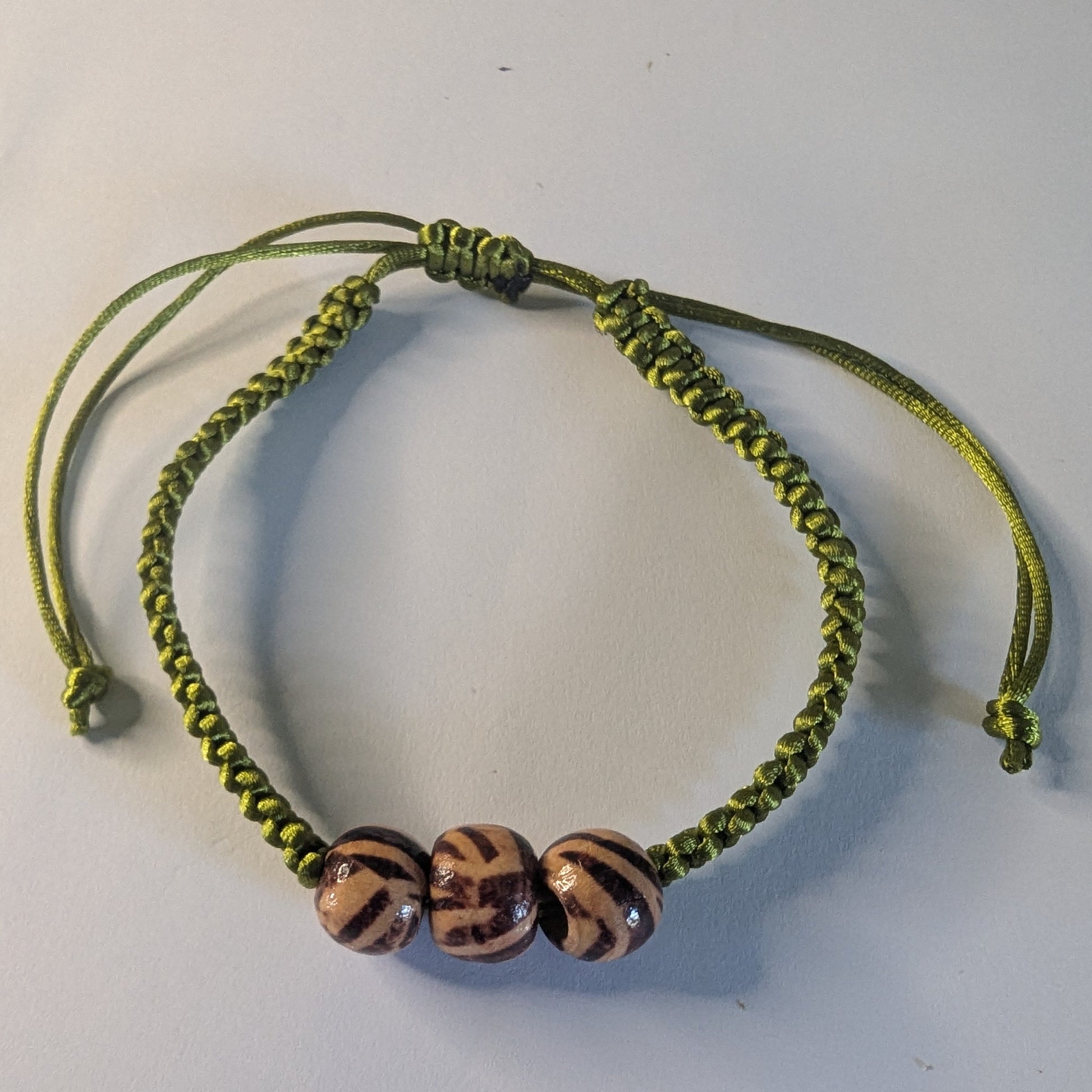 Green braided bracelet with three beads.