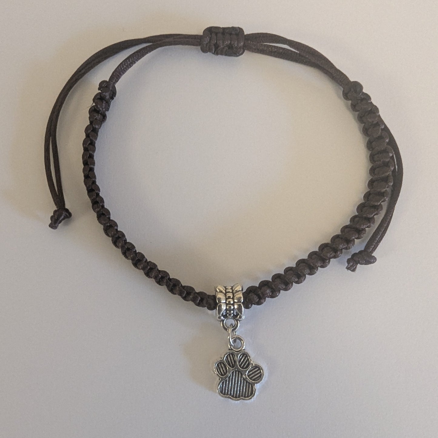 Brown braided bracelet with a silver paw charm 