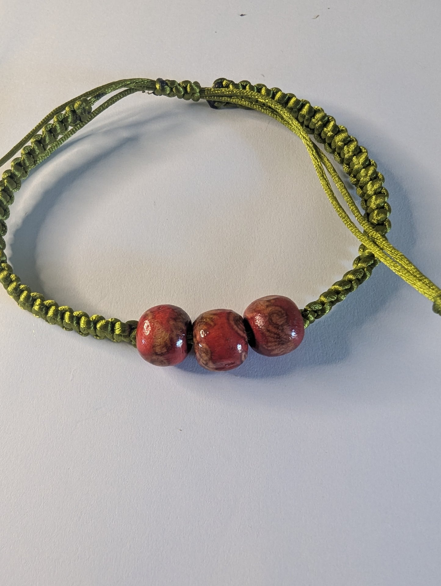 Green braided bracelet with red beads.
