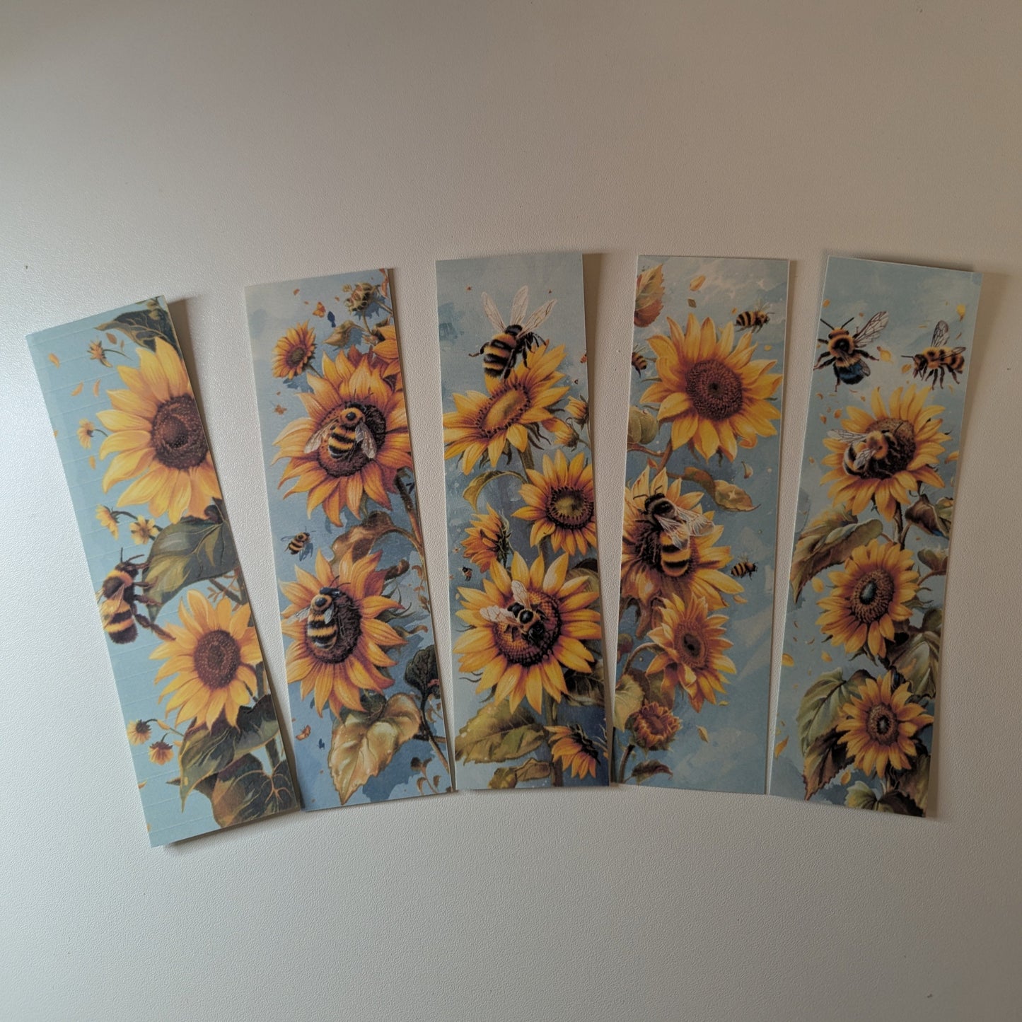 Five sunflower bookmarks with bees on a white background