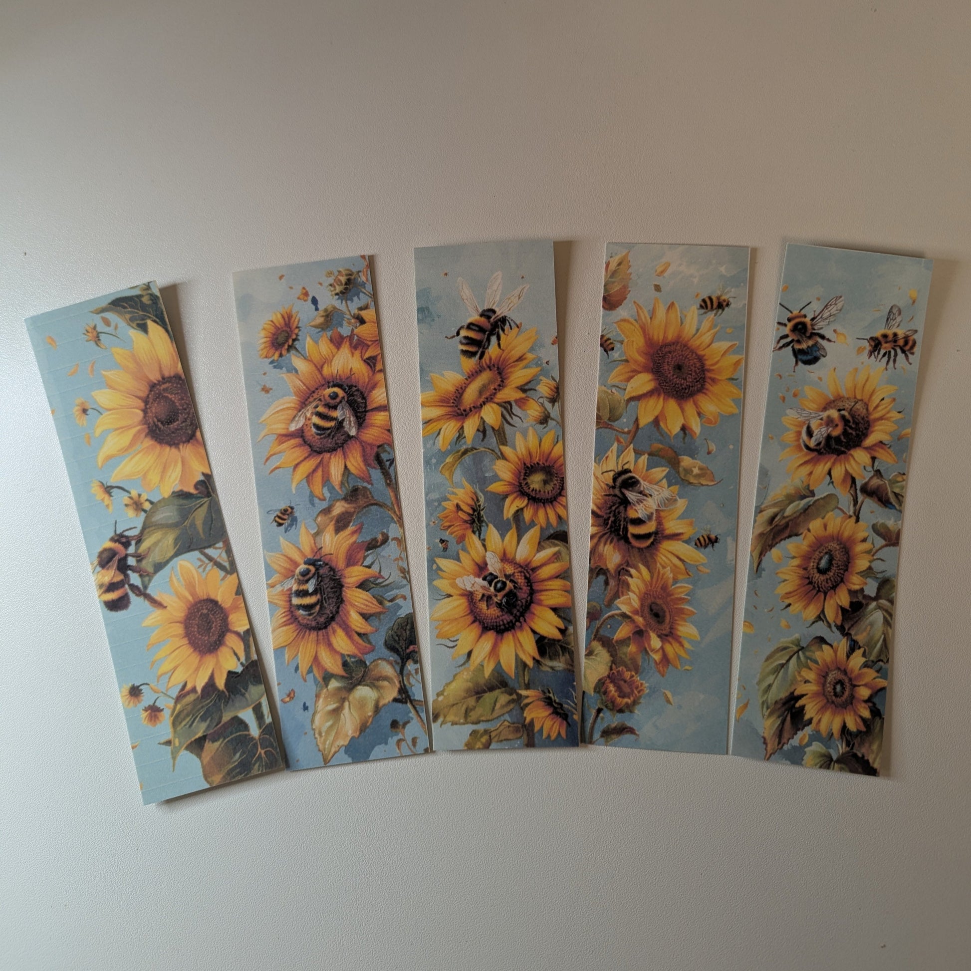 Five sunflower bookmarks with bees on a white background