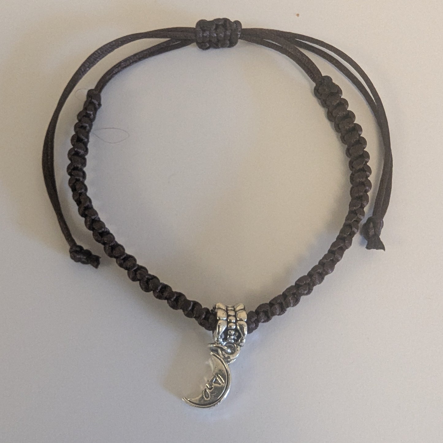 Brown braided bracelet with a silver charm 