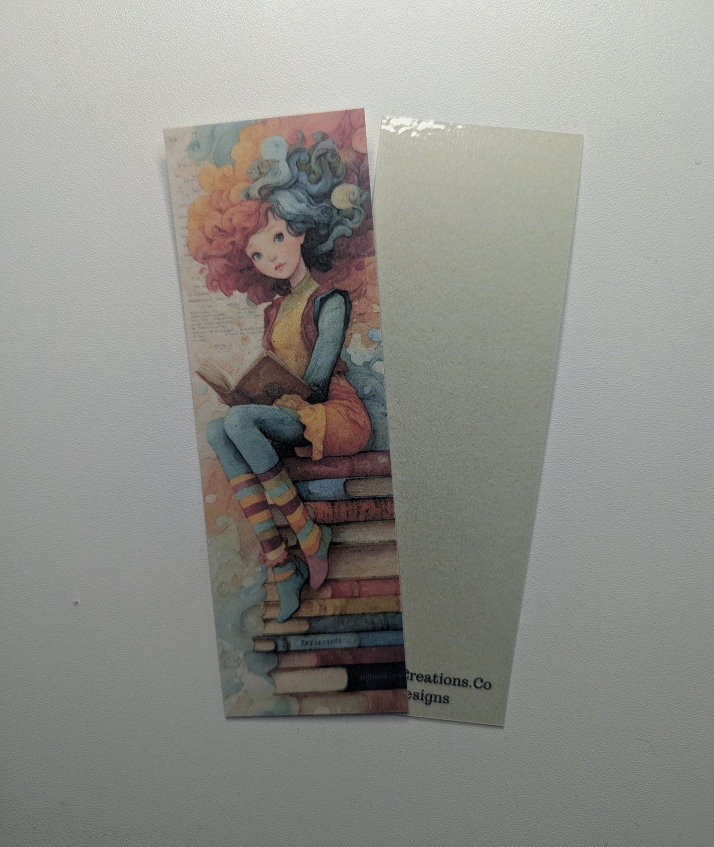 Colorful bookmark with a stylized illustration of a person sitting on books against a white background
