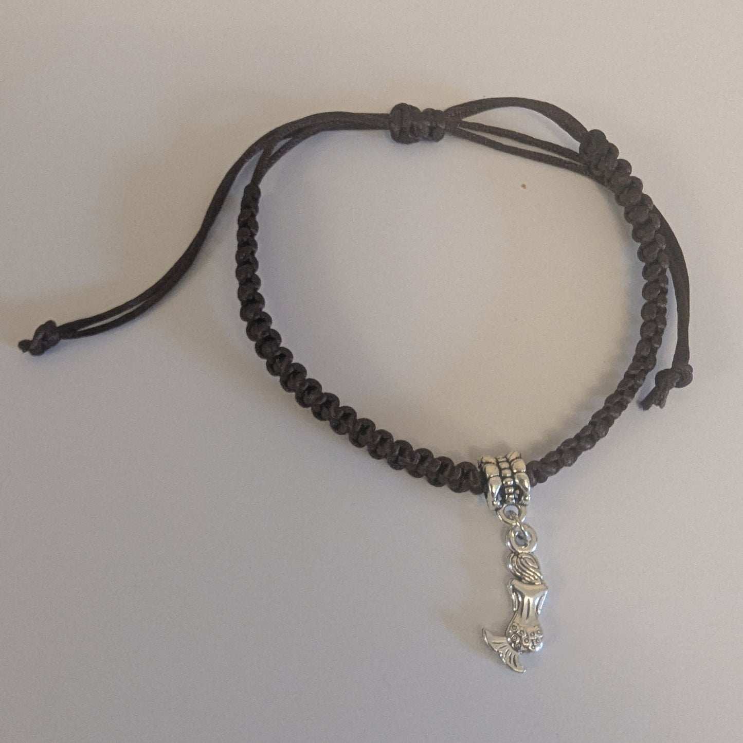 Brown braided bracelet with a silver charm 
