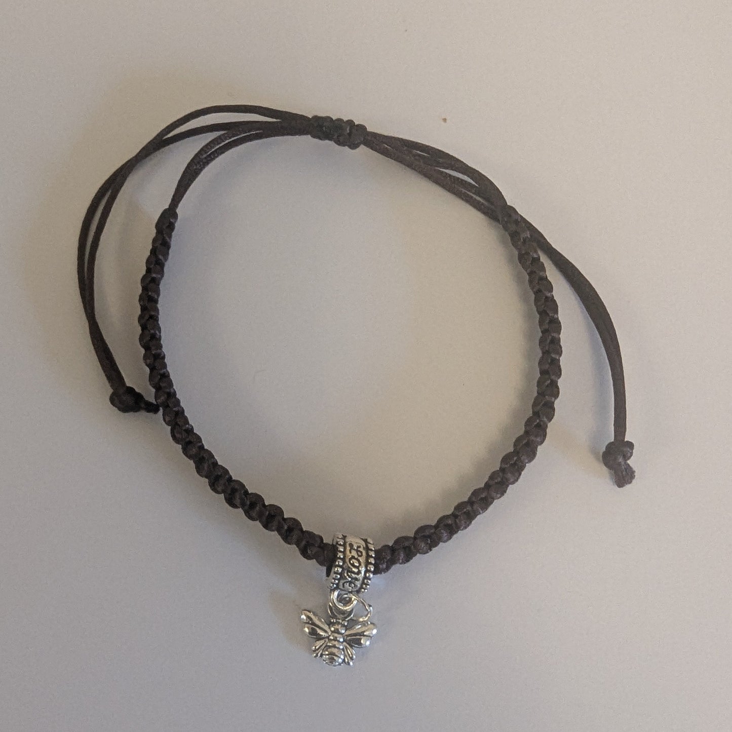 Brown braided bracelet with a silver charm 