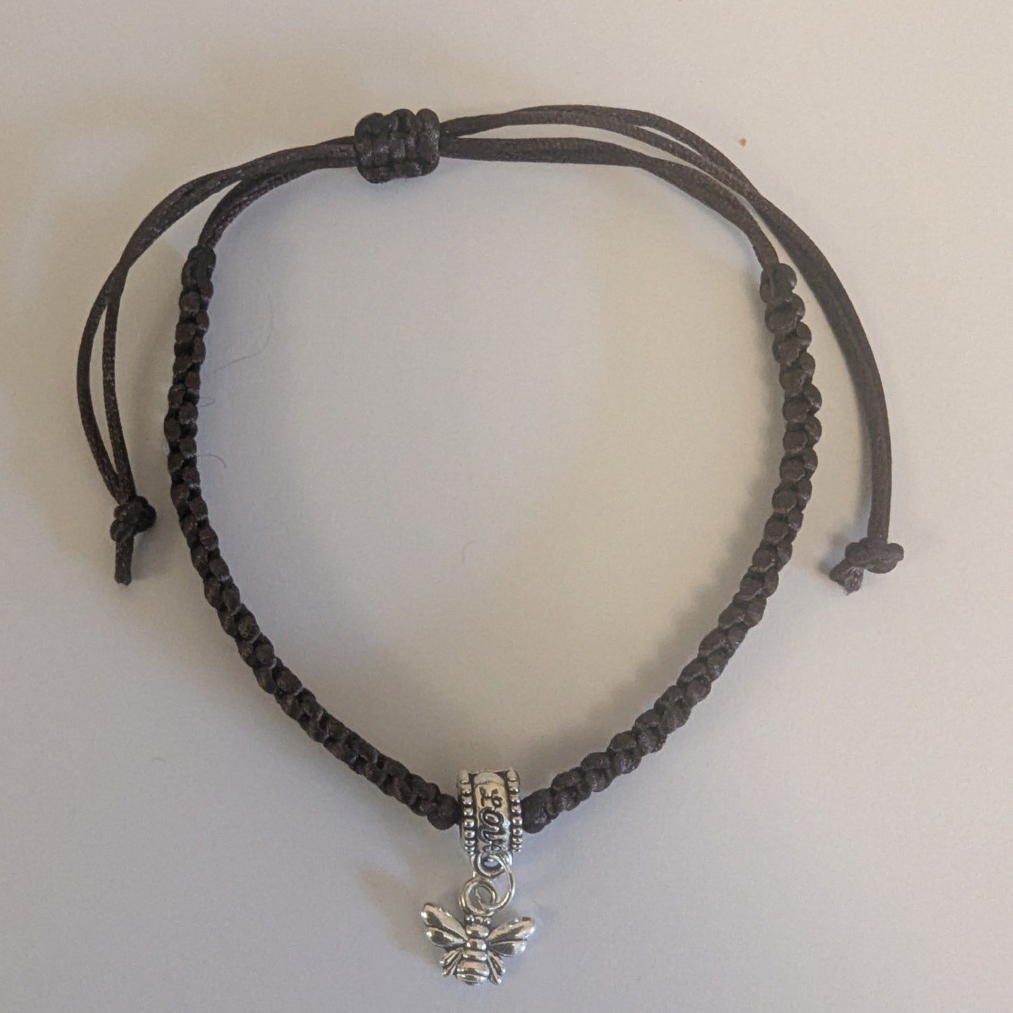 Brown braided bracelet with a silver bee charm 