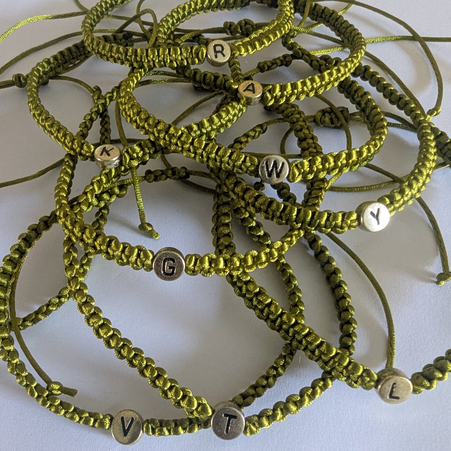 Green braided bracelets with letter beads.