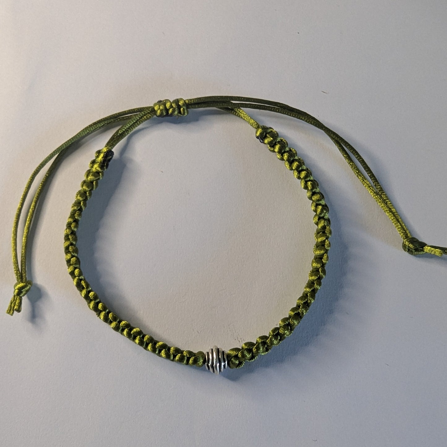 Green braided bracelet with a silver bead.