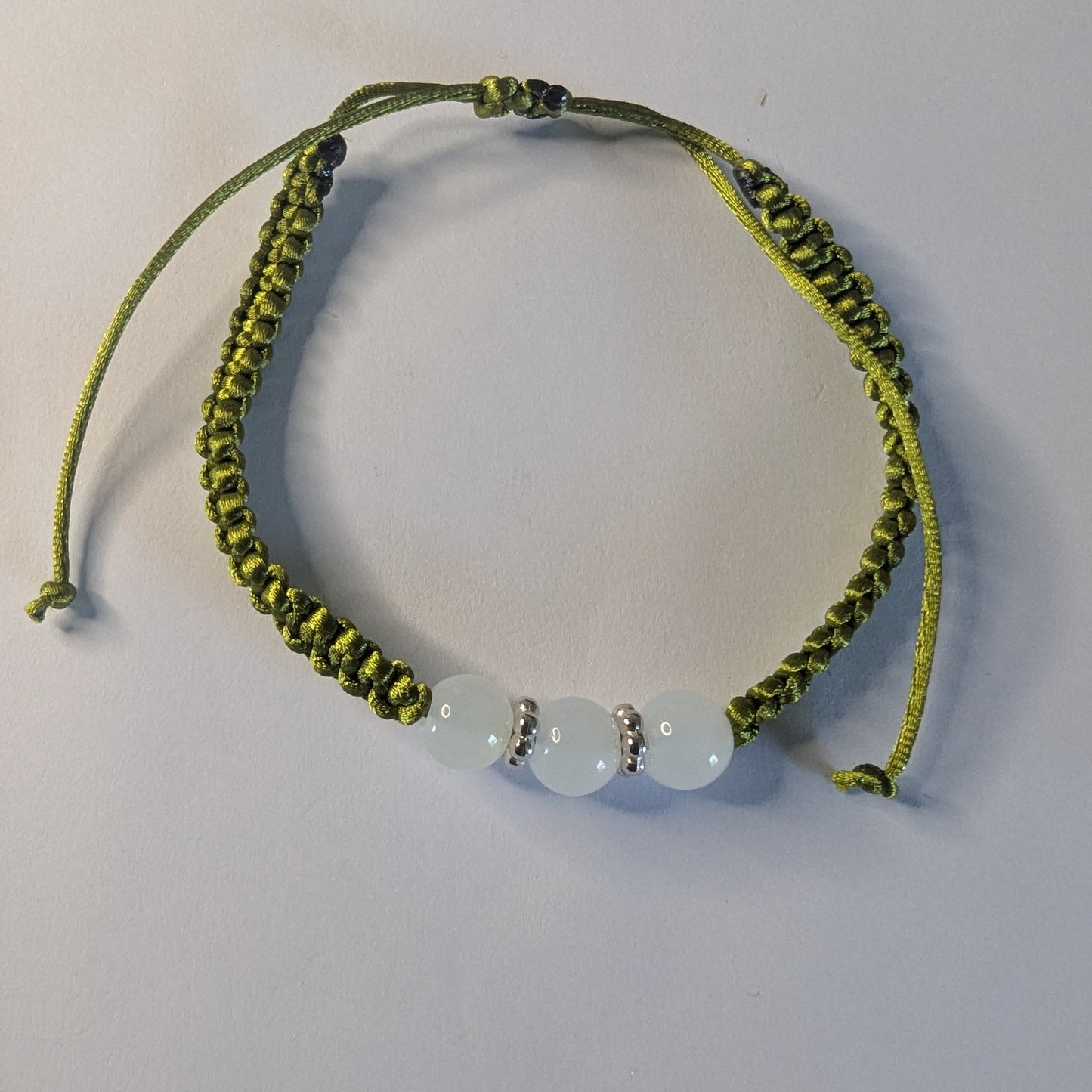 Green braided bracelet with three beads.